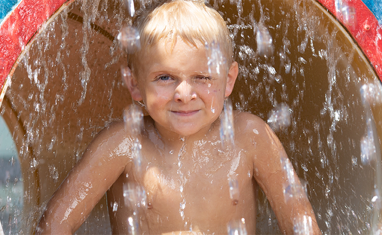 Young boy smiling as water pours on him at water park